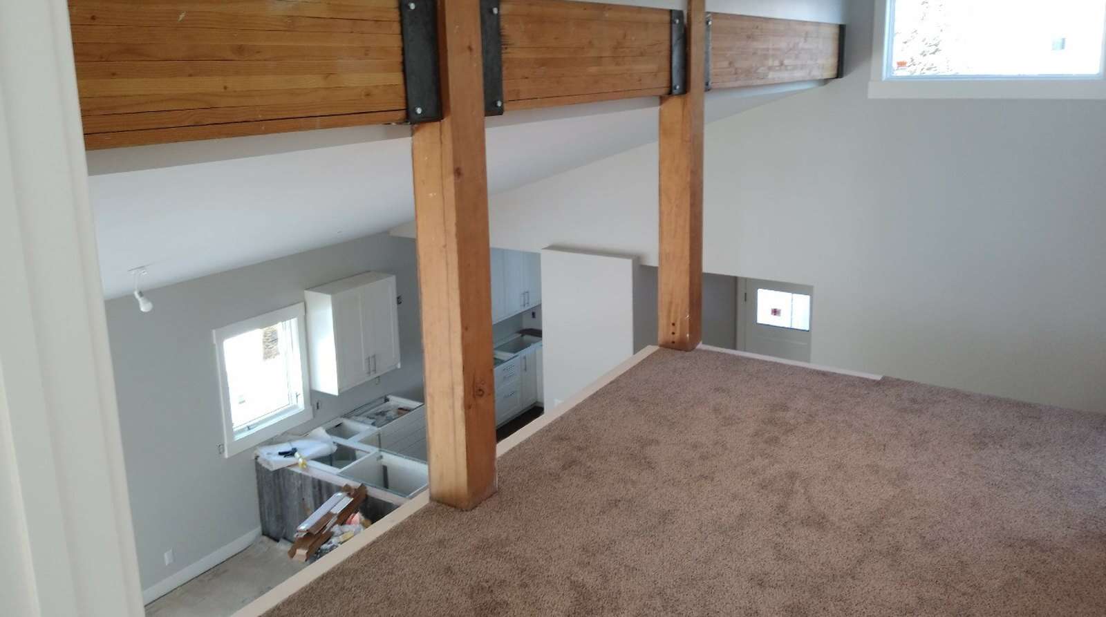 Newly laid carpet across a loft floor beside exposed timber posts and a steel-plated beam